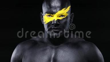 男子体育迷和健美运动员与黄色的脸艺术和黑色的身体油漆。 他的彩色画像